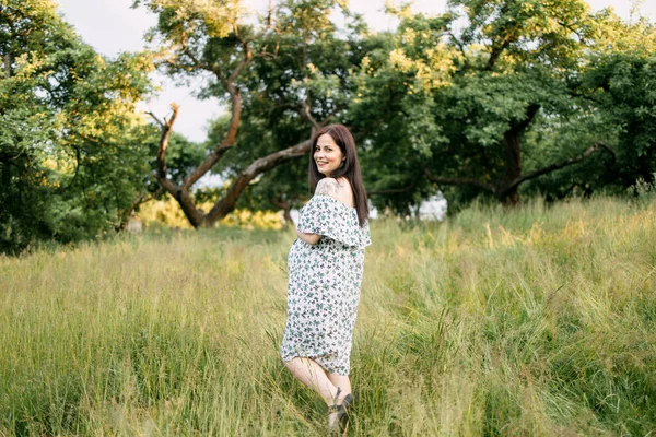 Femme enceinte en robe d'été debout au jardin vert — Photo