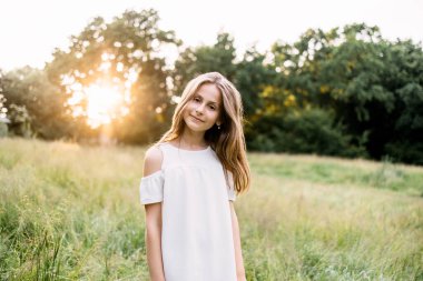 Tatlı kız gülümsüyor ve yaz bahçesinde kameraya bakıyor.