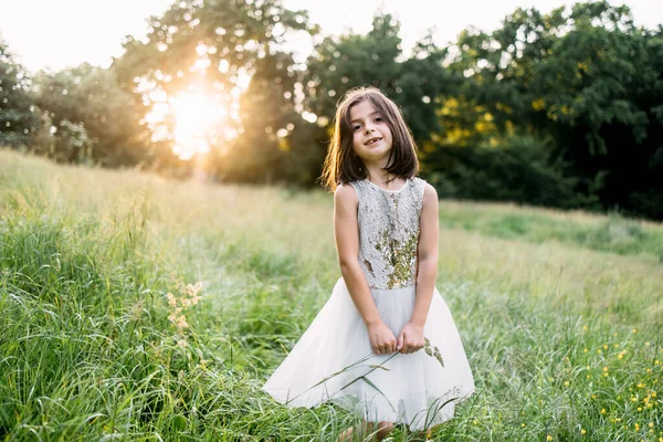 Criança brincalhão no vestido de verão andando entre grama alta — Fotografia de Stock