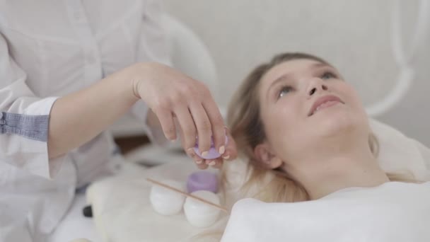 Imagem cortada de cosmetologist médico mulher com tigela de creme natural, close-up. Cosmetologists mãos que mantêm a nata de descascamento na pequena caixa violeta. Concentre-se na caixa com creme — Vídeo de Stock