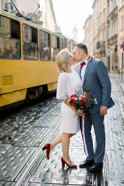 Boční pohled na dospělé pár objímání a líbání, při chůzi v krásném starém městě — Stock fotografie