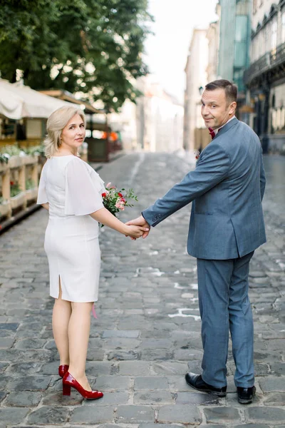 Celý tělo zpět pohled portrét zralého šťastného páru, na sobě luxusní oblečení, chůze po ulici — Stock fotografie