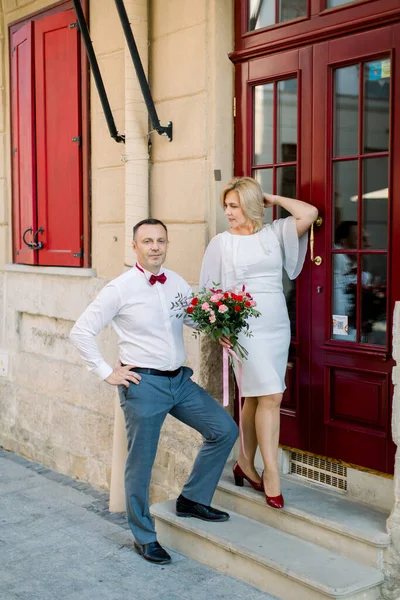 Heureux couple d'amour mature, debout à l'extérieur dans la ville, près de la belle porte rouge vintage — Photo