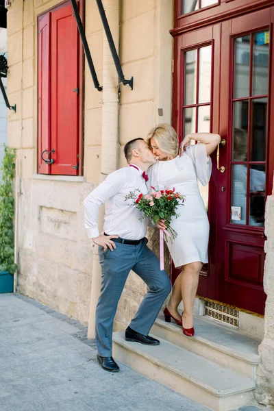 Felice coppia matura amorevole, in piedi all'aperto in città, vicino alla bella porta rossa vintage — Foto Stock