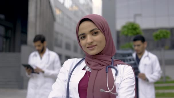 Група арабських медиків стоїть на відкритому повітрі перед сучасною клінікою. — стокове відео
