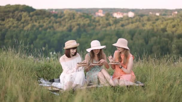 Güzel kızlar Fransız yemeği yiyor salyangoz yiyor, piknikte battaniyenin üzerinde oturuyor. — Stok video