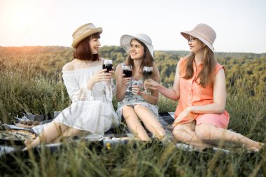 Gülümseyen en en iyi arkadaşlar çimenlerde kırmızı şarap içiyorlar..