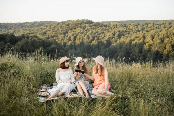 Três lindas amigas bonitas se divertindo, saúde e beber vinho, e desfrutar de piquenique ao ar livre — Fotografia de Stock