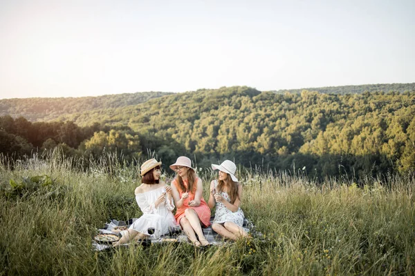 Três amigos femininos felizes elegantes que se divertem na festa de piquenique ao ar livre, comendo comida gourmet francesa saborosa — Fotografia de Stock