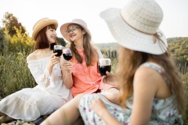 Elbise ve şapka giymiş güzel bir kızın arkadaşlarıyla piknik yaptığı bulanık bir manzara.