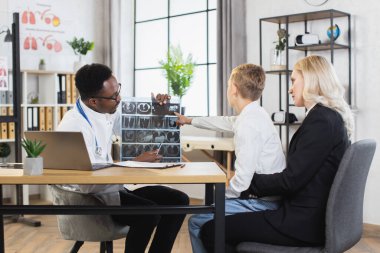 Afrikalı çocuk doktoru, tomografi taramasını genç hasta ve ilgili annesine açıklıyor.