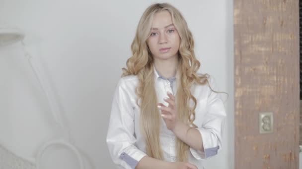 Retrato de media longitud de la bella joven rubia caucásica médico cosmetólogo esteticista, posando a la cámara de interior en el centro de cosmetología moderna. — Vídeo de stock