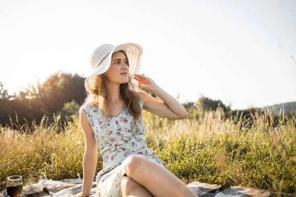 Junge Frau schaut weg, sitzt auf Plaid mit leckerem Essen und Früchten und genießt den Sommertag. — Stockfoto