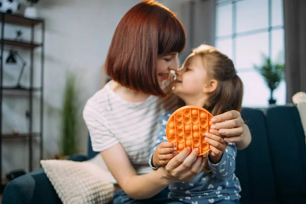 Sevimli bir aile, güzel bir anne ve tatlı bir kız, evdeki kanepede oturup pop pit oynuyorlar. — Stok fotoğraf