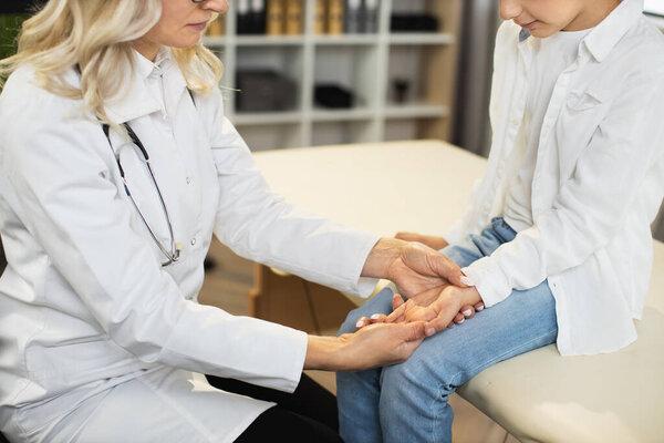 Female doctor checking pulse of caucasian boy at clinic