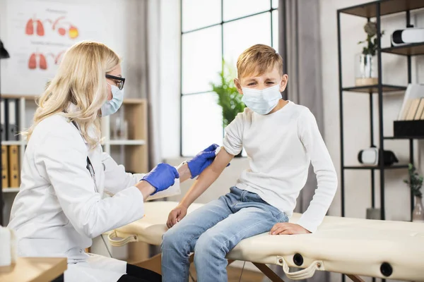 Médica qualificada vacinando menino na clínica — Fotografia de Stock