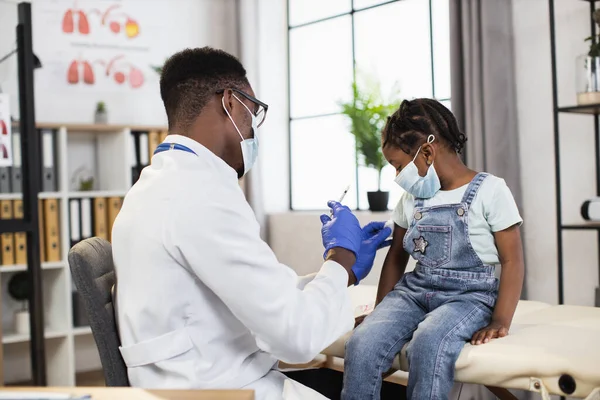 Trabalhador médico preto fazendo injeção para criança bonita — Fotografia de Stock