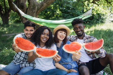 Çoklu etnik arkadaşlar doğada lezzetli karpuzun tadını çıkarıyorlar.
