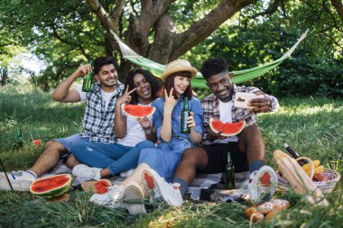 Dört arkadaş bahçede akıllı telefondan selfie çekiyor.