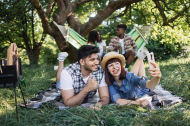 Akıllı telefonlu piknikteki neşeli farklı arkadaşlar