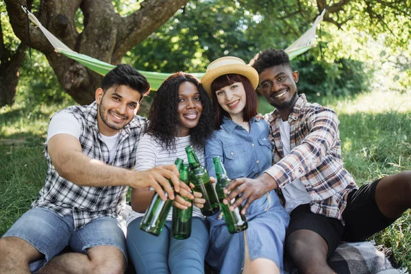 Multi amis ethniques posant au jardin avec de la bière dans les mains — Photo