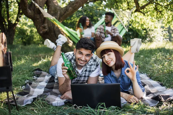 Amis divers positifs utilisant un ordinateur portable au jardin vert — Photo