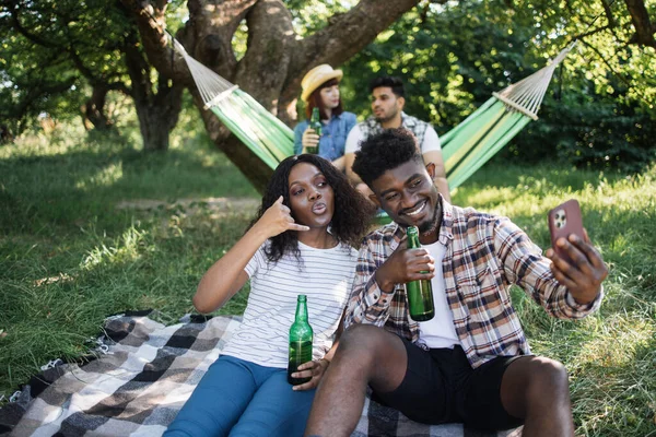 Divers amis avec smartphone relaxant au jardin verdoyant — Photo