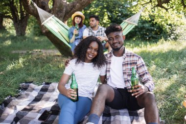 Dört çok ırklı insan bahçede yaz pikniği yapıyor.