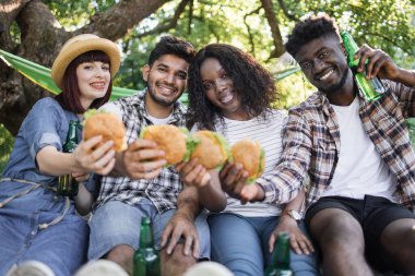 Dört arkadaş hamburger ve birayla pikniğin tadını çıkarıyor.
