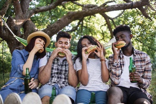 Divers amis boire de la bière et manger des hamburgers en plein air — Photo