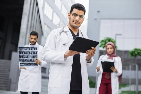 Tre giovani medici, che lavorano con tablet pc, radiografie e cartelle cliniche dei pazienti fuori dall'ospedale — Foto Stock