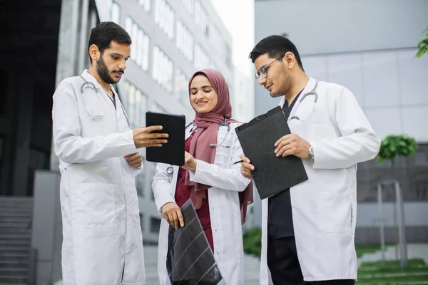 Arabian team medico avendo discussione all'aperto di fronte alla clinica, guardando schermo tablet pc — Foto Stock