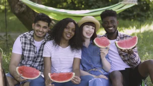 Позитивная молодежь держит на открытом воздухе ломтики арбуза — стоковое видео