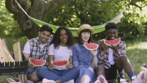 Çok kültürlü insanlar piknikte olgun karpuz yiyor. — Stok video