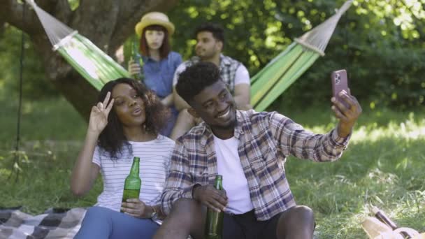 Doğada piknik yaparken akıllı telefon kullanan dört arkadaş. — Stok video