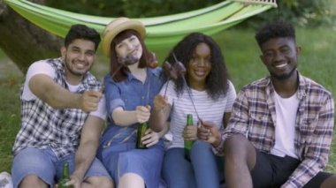 Arkadaşlar piknikte ızgara sosis ve soğuk biranın keyfini çıkarıyorlar.