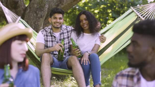 Чотири радісні друзі мають пікнік в літньому саду — стокове відео
