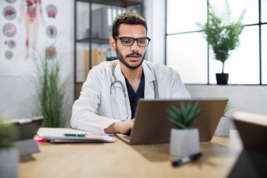 Arap doktor doktor, dizüstü bilgisayara bakıyor ve tıbbi tavsiyelerde bulunuyor.