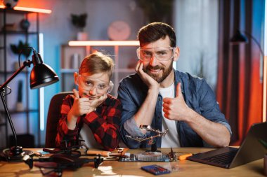 Baba ve oğul dizüstü bilgisayarı tamir ettikten sonra başparmak gösteriyor.