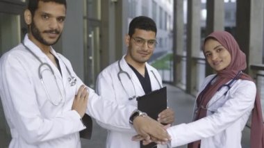 İki yakışıklı erkek doktor ve tesettürlü güzel bayan meslektaşları el ele tutuşuyorlar.