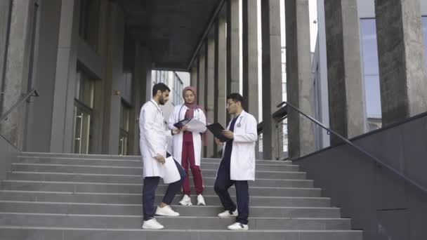 Trois jeunes médecins multiethniques excités collègues, vomissant des papiers — Video