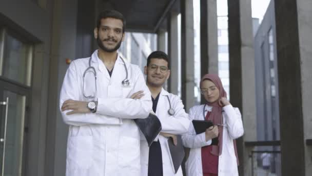 Team arabisch-malaiischer Medizinstudenten zeigt Daumen hoch, während sie vor moderner Klinik in einer Reihe stehen — Stockvideo