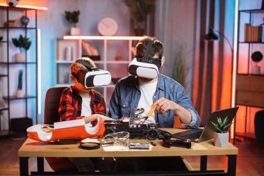 Baba, oğluna VR gözlükleriyle oyuncak araba tamir etmede yardım ediyor.