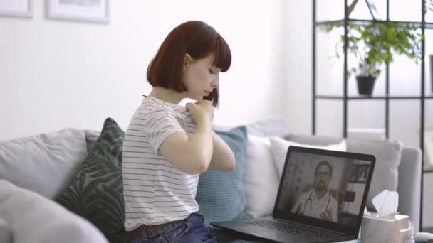 Молодая больная женщина в повседневной одежде консультируется по видеосвязи с врачом мужского пола — стоковое видео
