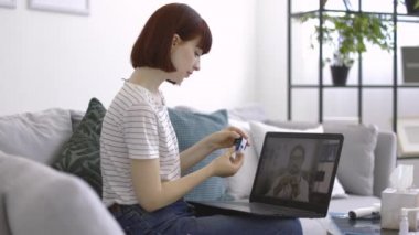 Nabız oksimetresi olan bir kadın dizüstü bilgisayarında erkek doktorun eğitim videosunu izliyor.
