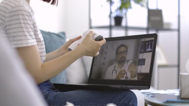 Vrouw, meten van haar lichaamstemperatuur met contactloze thermometer onder toezicht van arts — Stockvideo