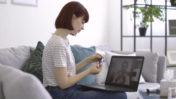 Mulher com oxímetro de pulso nas mãos assistindo vídeo educativo do médico masculino no laptop — Vídeo de Stock