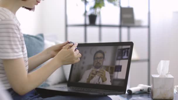 Mujer tratando de oxímetro de pulso, escuchando al médico masculino a través de chat de vídeo en línea en la pantalla del ordenador portátil — Vídeos de Stock