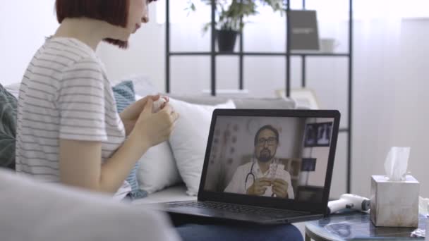 Hombre médico caucásico, sosteniendo píldoras en la mano, consultando en línea a su paciente femenino sobre el tratamiento — Vídeo de stock