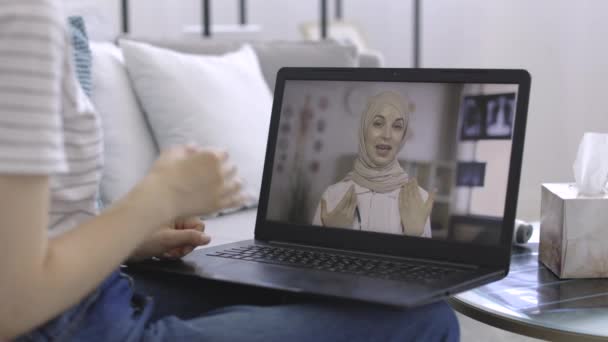 Paciente irreconocible mujer hablando en línea en el ordenador portátil con terapeuta médica musulmana mujer en hijab — Vídeos de Stock